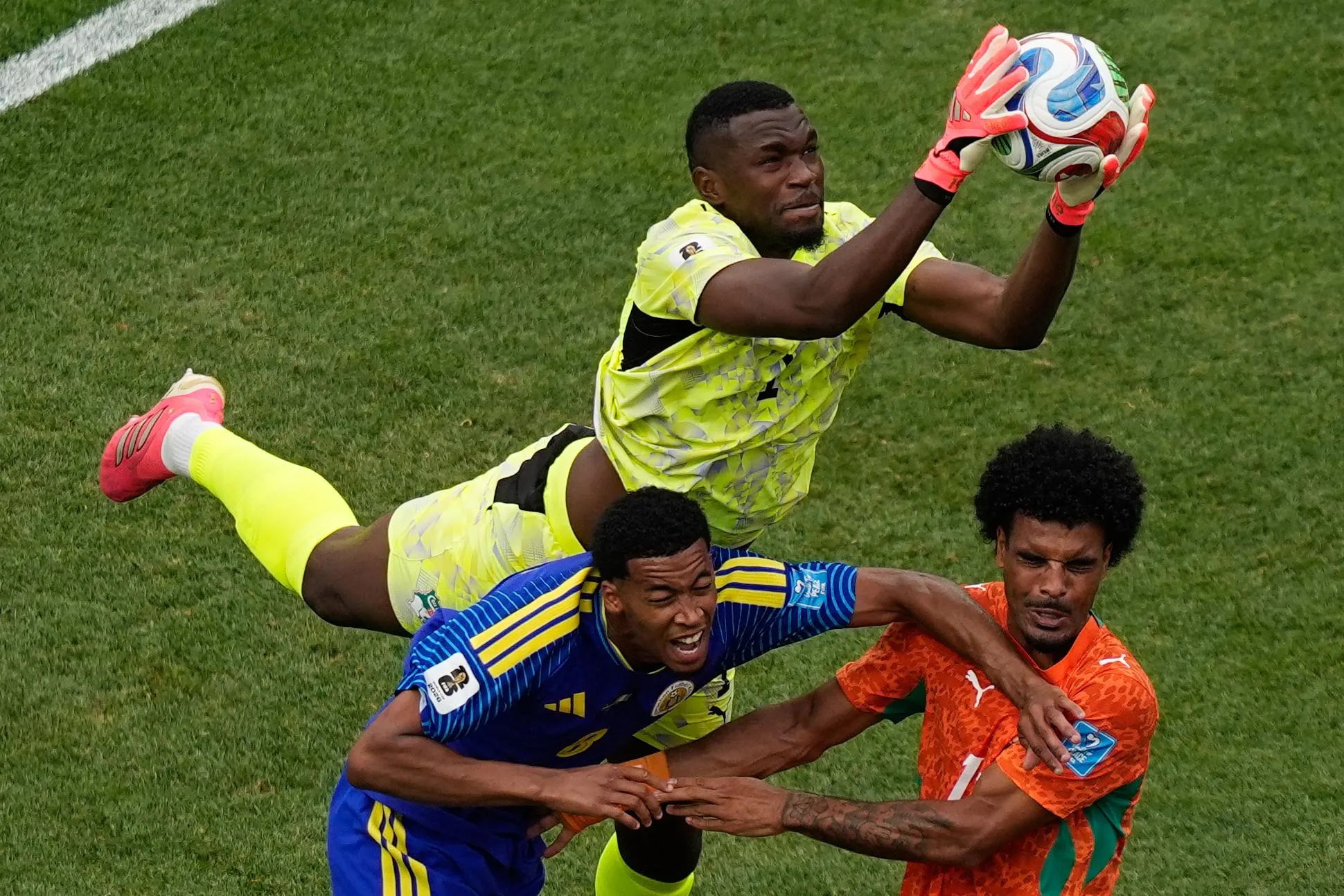 Ivory Coast goalkeeper Yahia Fofana (1) claims the ball and barging Curaçao's Livano Comenencia (8) and Ivory Coast's Christopher Operi (13).
