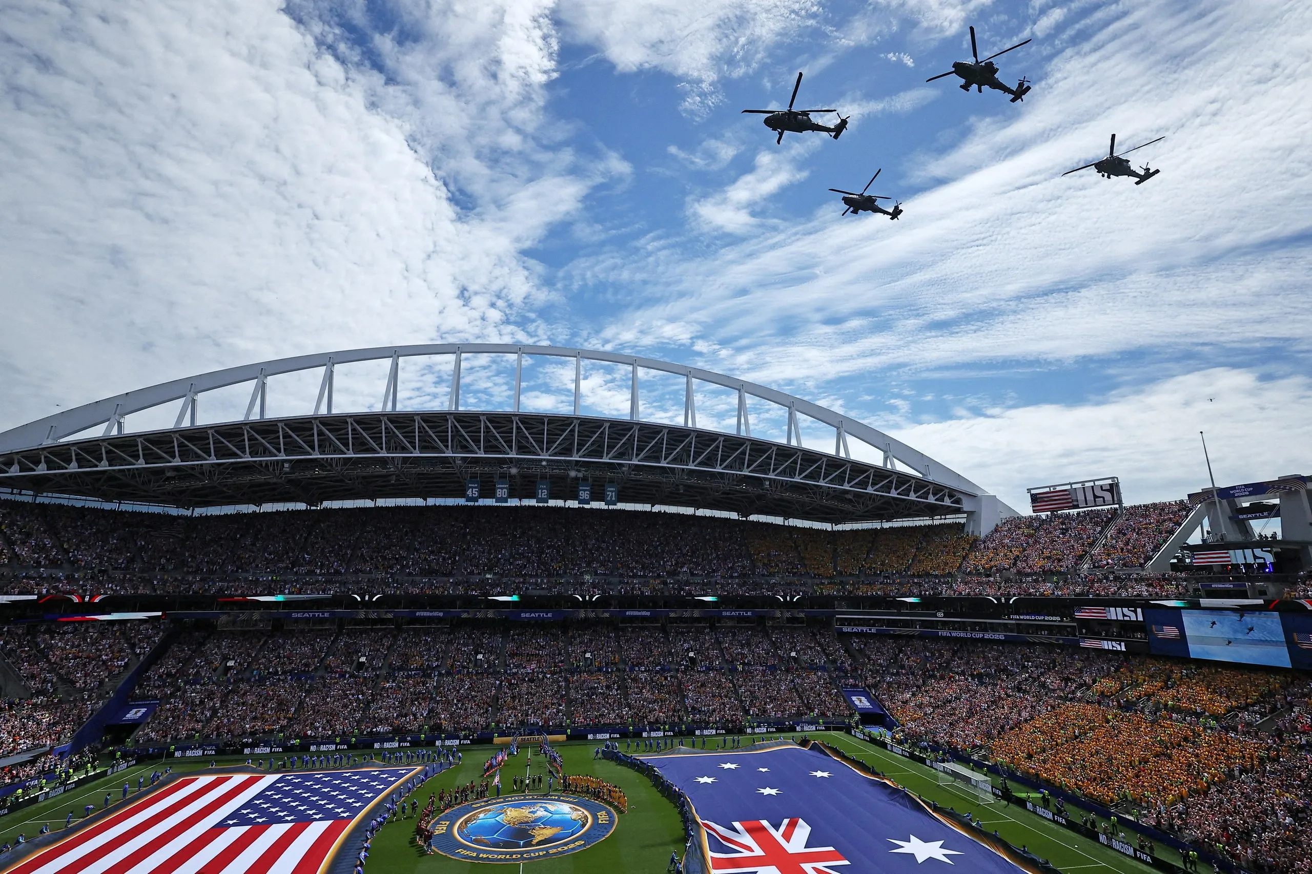 Players line up during the national anthems before the match as military helicopters fly overhead