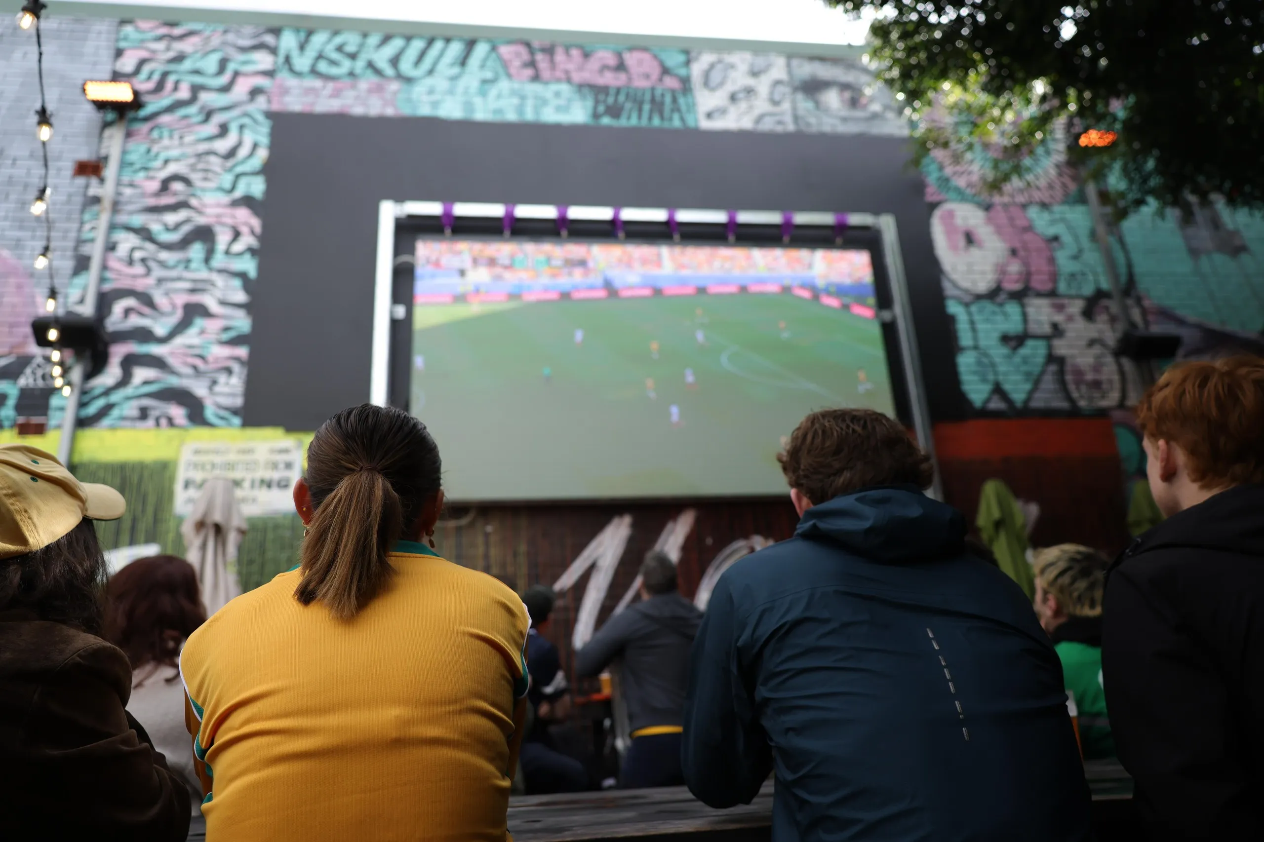A big screen shows the game.
