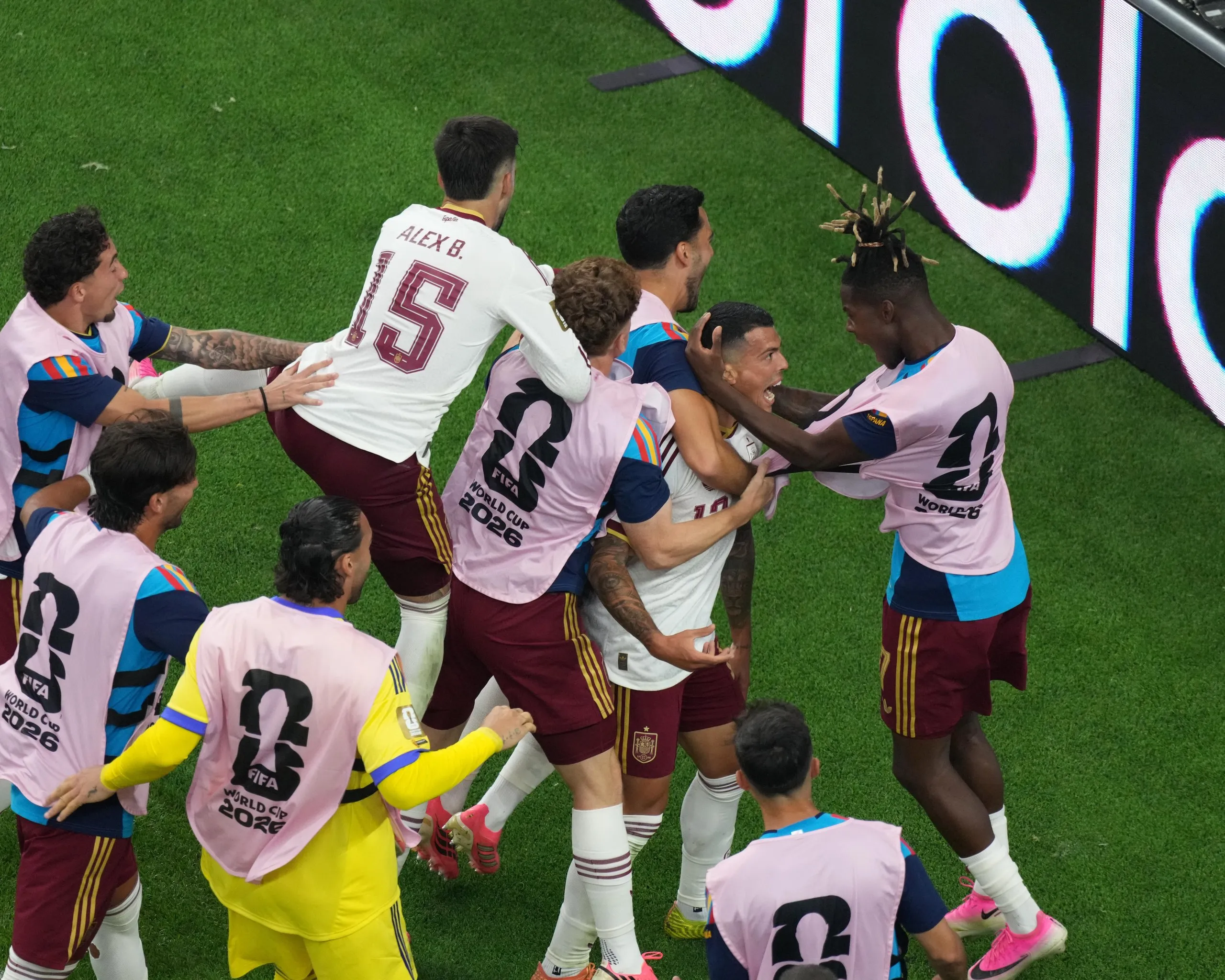 The Spain player Pedro Porro is hugged by multiple teammates, including substitutes, after scoring in the 2026 World Cup semi-final against France in Dallas.
